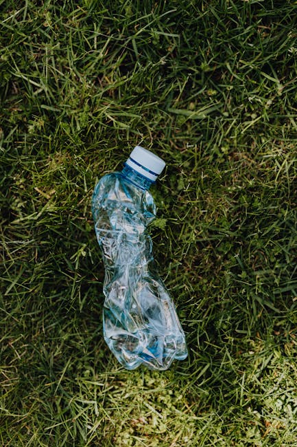 A pile of discarded household rubbish and waste materials scattered on dry, brown grass and twigs outdoors. The collection includes various cardboard boxes, some flattened and others still intact, as 